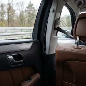 Eine störend vibrierende Kunststoffverkleidung im Heck eines fahrenden Kombis löst sich sichtbar von der Seitenwand.